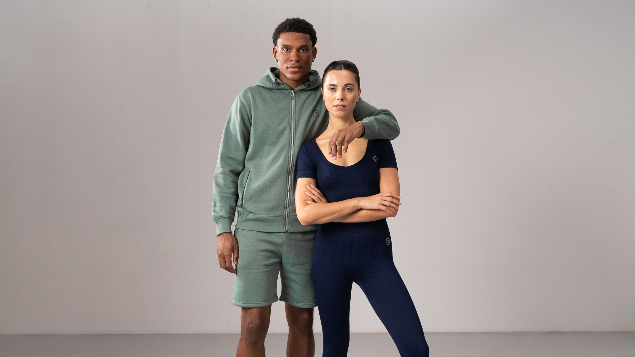 MAN IN GREEN SHORTS AND HOODY WOMAN IN NAVY YOGA SET
